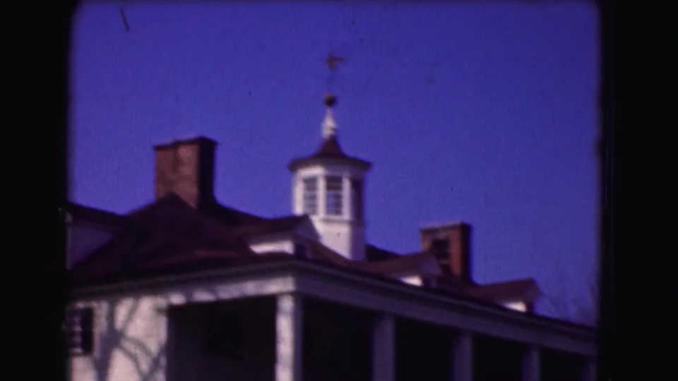 1975 8mm frame from Washington DC metadata showing the upper facade of a colonial-style historic building with columns, chimneys, and cupola.
