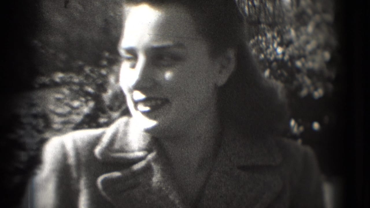 Woman in a dark coat smiles outdoors in a grainy black-and-white close-up.