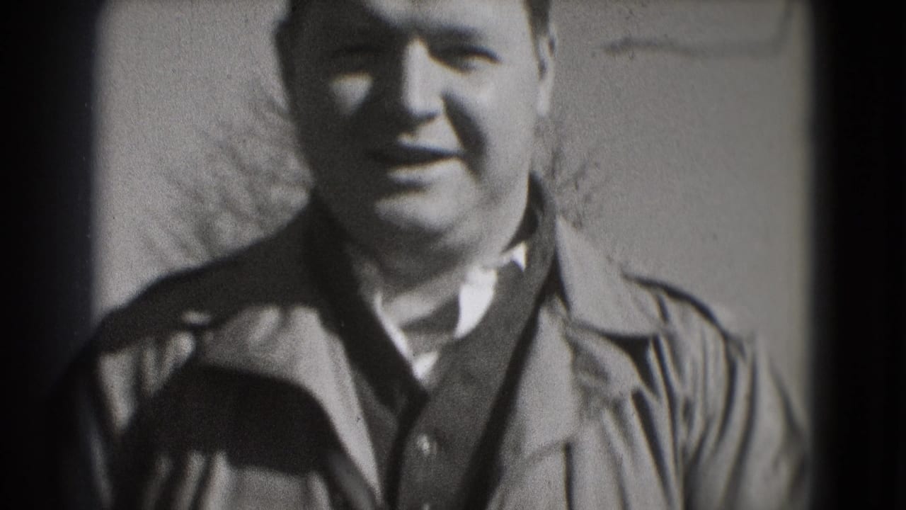 Man in a jacket smiles toward the camera in a soft-focus close shot.