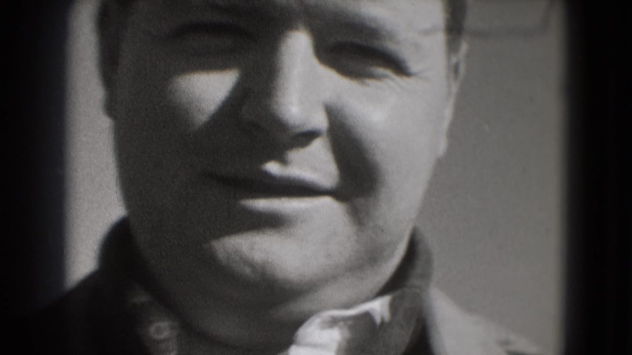 A close 8mm frame shows a smiling adult man, tightly cropped with soft exposure and visible film grain.