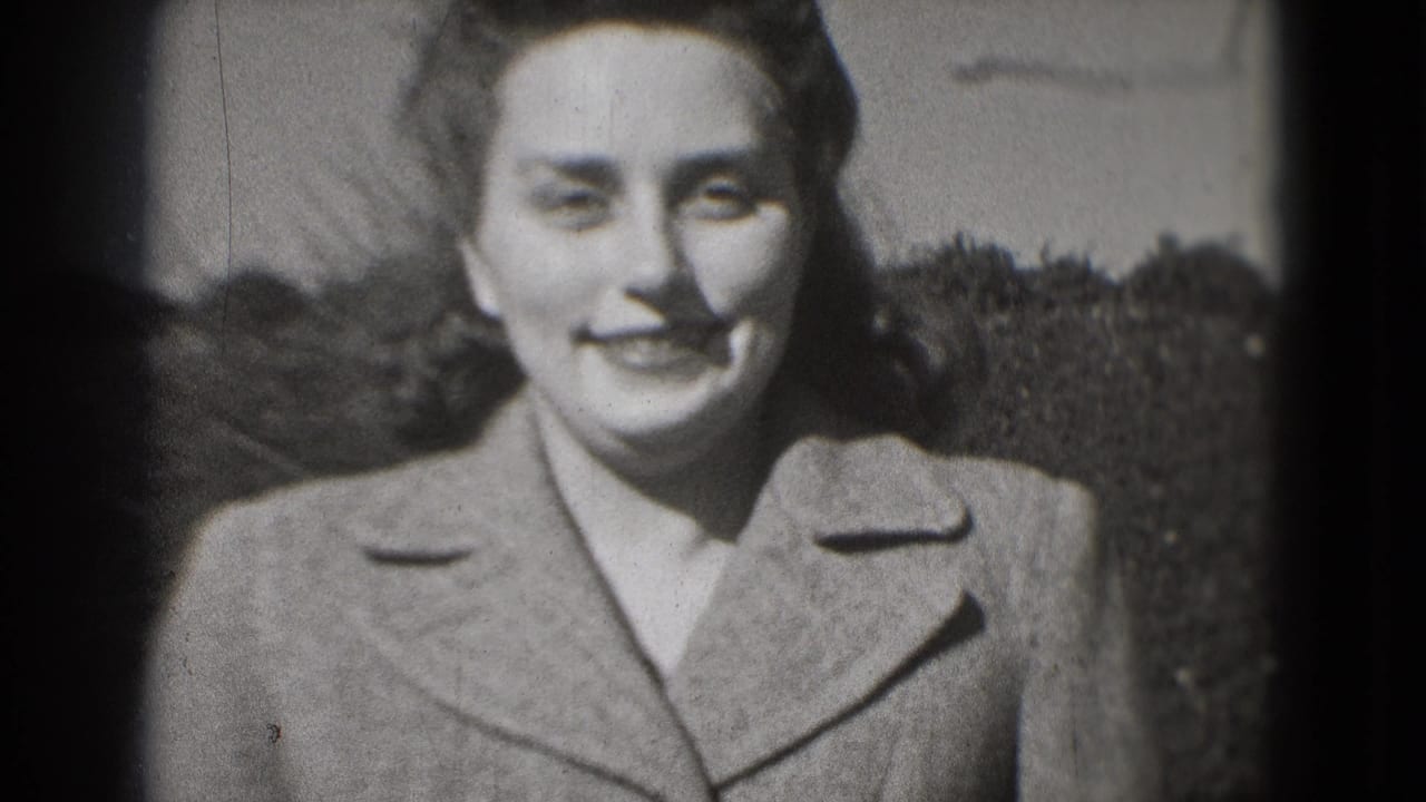 Young woman in a coat smiles directly at the camera in black-and-white 8mm footage from a Washington, DC home-movie context.