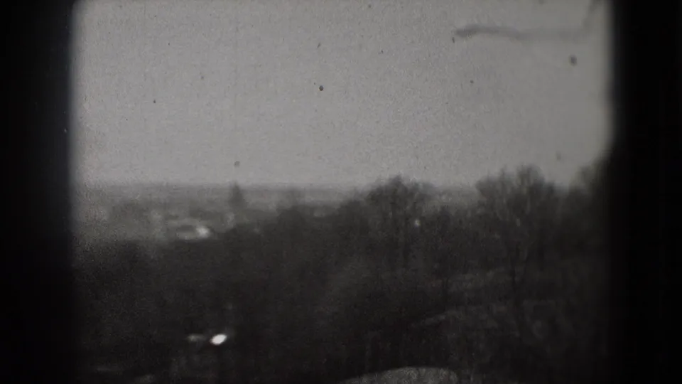 Soft black-and-white 8mm view of a distant hazy cityscape with trees in the foreground, associated with Washington, DC by metadata.