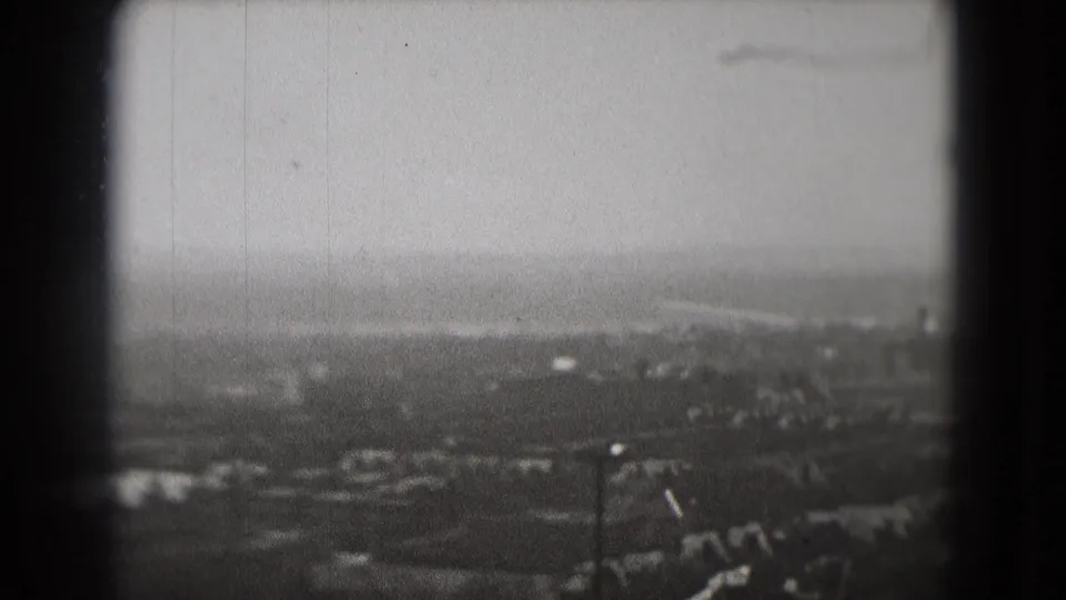 1975 Washington, DC aerial home-movie view showing a distant hazy skyline, buildings, trees, and cloudy sky through 8mm frame edges.