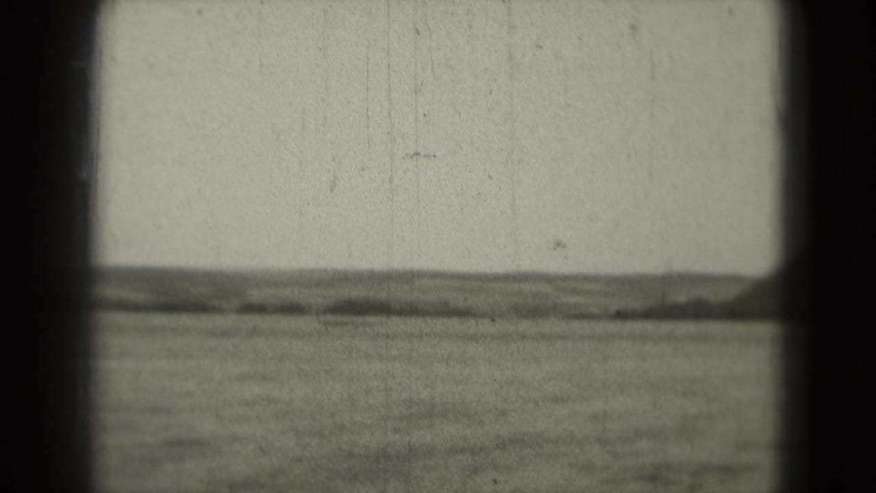 Open water and distant low hills seen through dark 8mm frame edges.