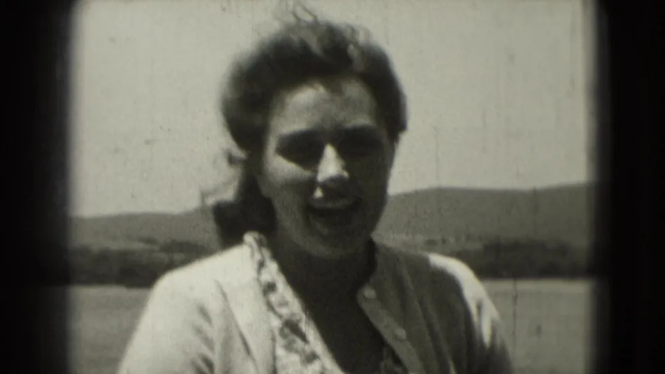 Adult woman faces the camera in a close 1975 Washington DC 8mm frame, with wind in her hair and a low horizon behind her.