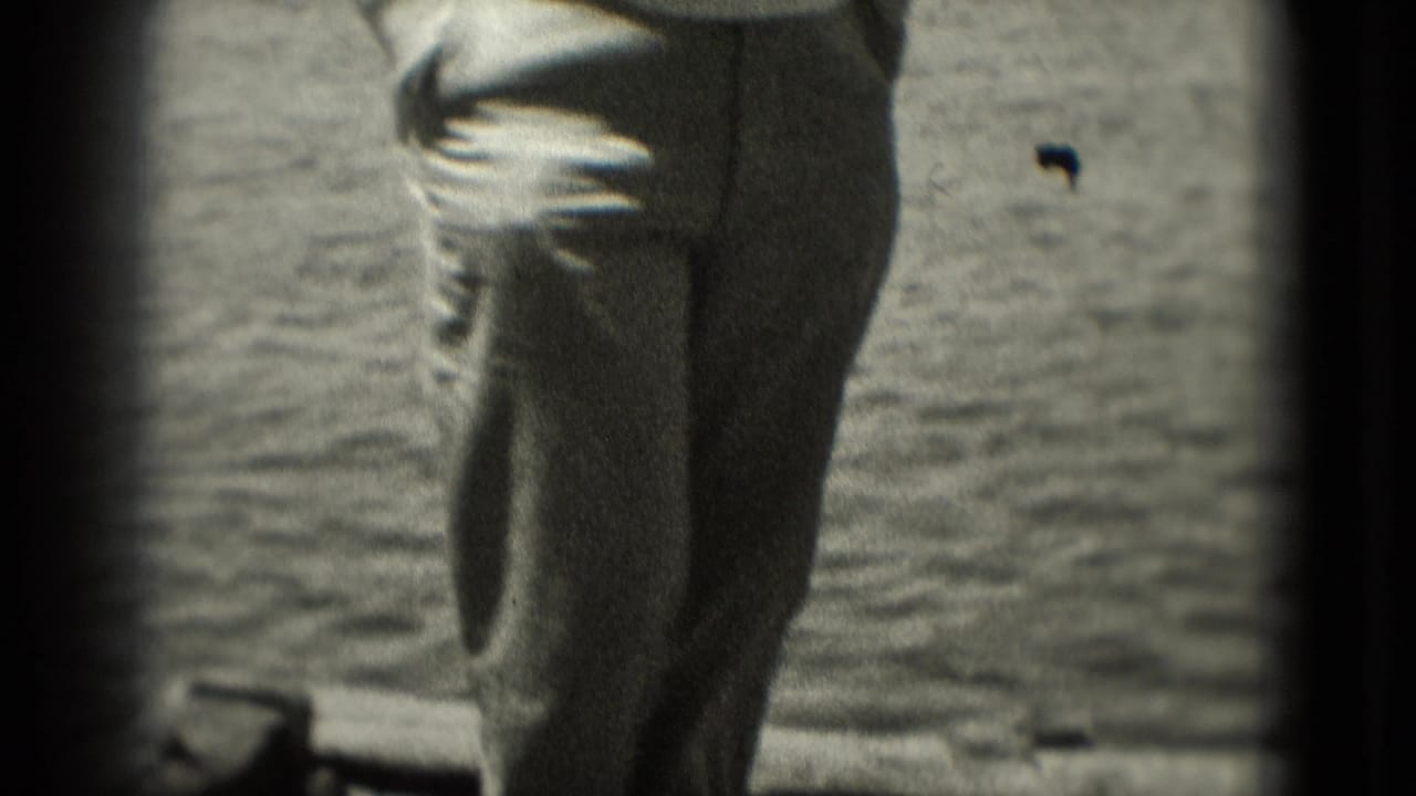 1975 Washington, DC home-movie frame with a man in slacks partly cropped as he stands or walks near an open water background.