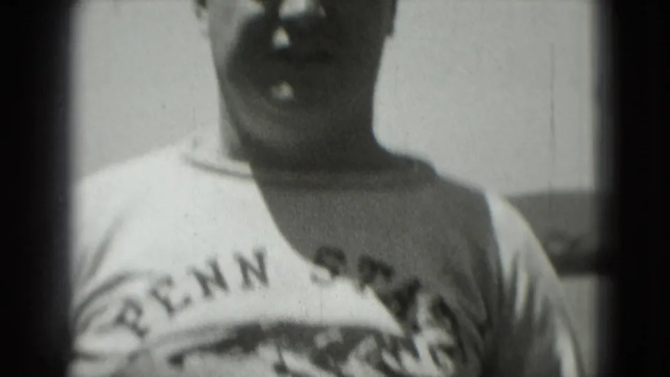 Man wearing a Penn State shirt faces the camera outdoors in grainy 1975 Washington, DC 8mm footage.