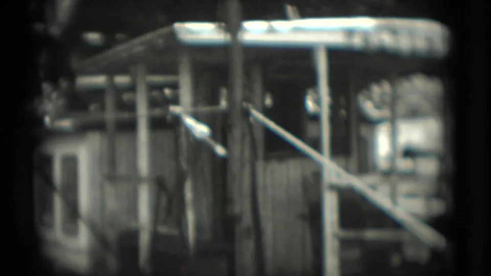 Final 1975 Washington, DC frame holds on the FALCON-marked enclosure, showing metal bars, a diagonal rail, dark surroundings, and a small structure nearby.