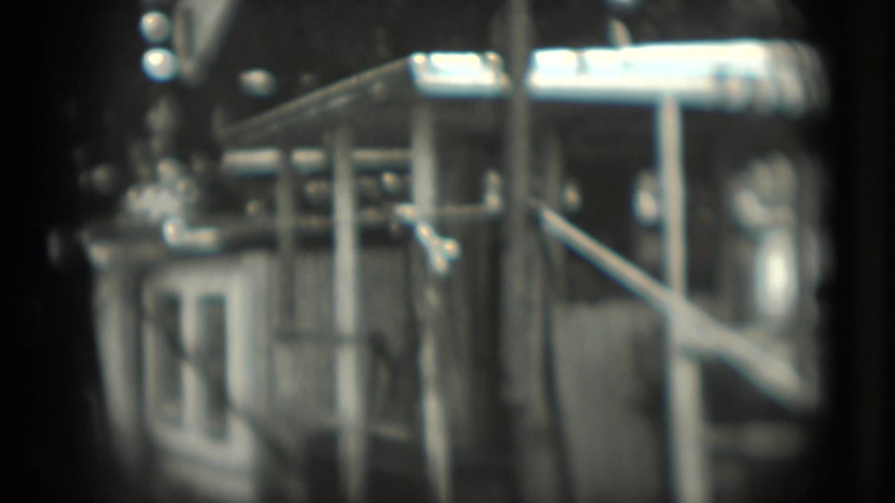 Soft black-and-white view of metal enclosure structures and railings.