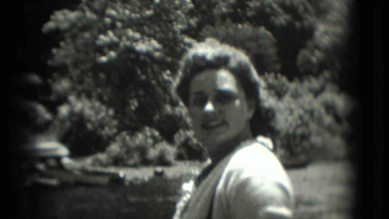 Woman outdoors turns toward the camera with trees behind her.
