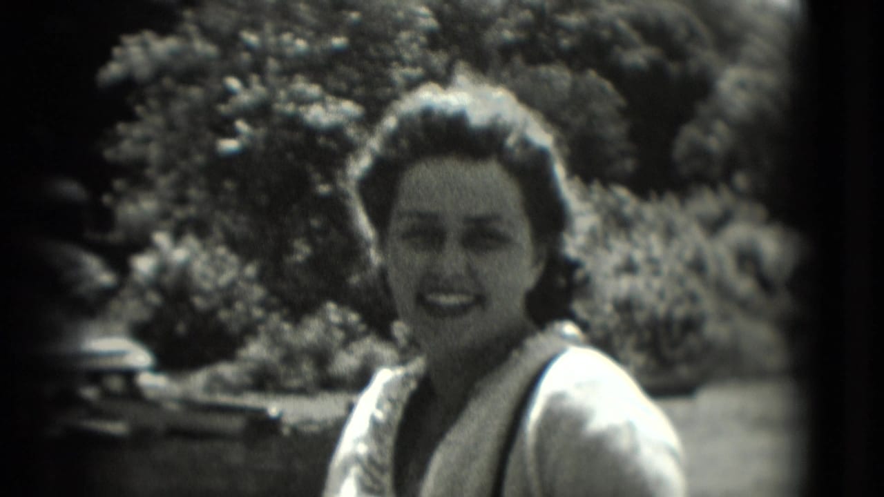 Woman smiles toward the camera in a sunlit outdoor setting.