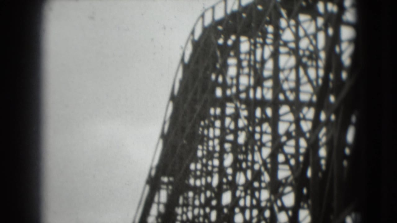 1975 8mm frame looking up at the lattice supports of a wooden roller coaster in Washington, DC metadata context.