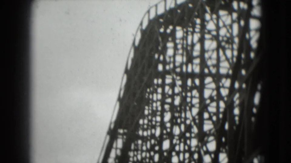 1975 8mm frame looking up at the lattice supports of a wooden roller coaster in Washington, DC metadata context.