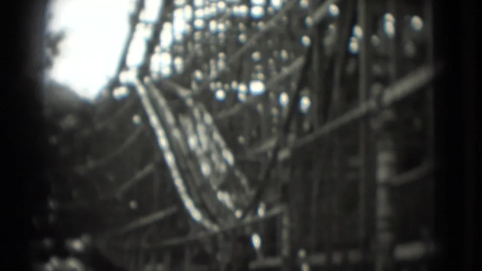 Final 1975 Washington DC frame with the wooden roller coaster track and support beams filling the view, softened by handheld 8mm motion.
