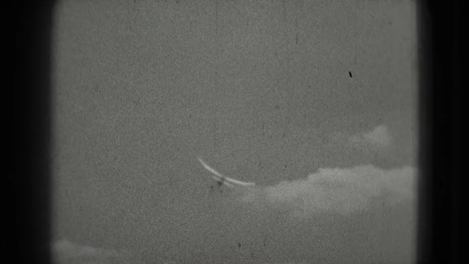 A small aircraft is seen against cloud cover in archival 8mm footage from a Washington, DC travel reel.