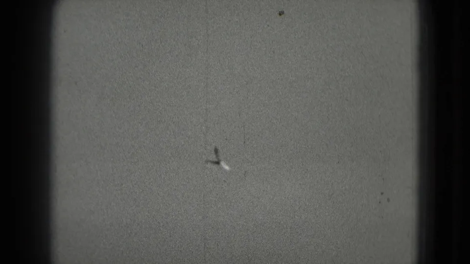 A distant aircraft appears in open sky in vintage 8mm footage linked by metadata to Washington, DC in 1975.