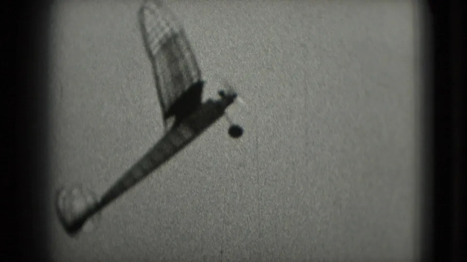 The model airplane rises into the sky, framed by grainy 8mm home-movie footage from the Washington DC clip.