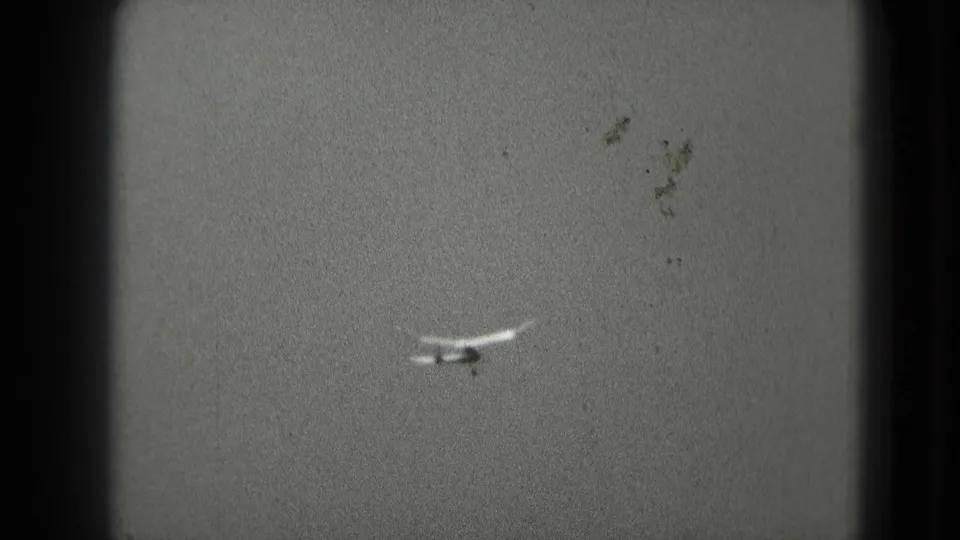 The model airplane appears smaller and farther away against a bright sky near the end of the 8mm clip.