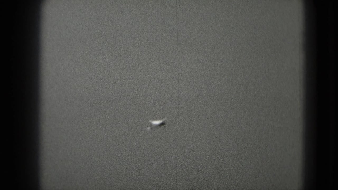 Distant airplane reduced to a bright speck in a gray sky.