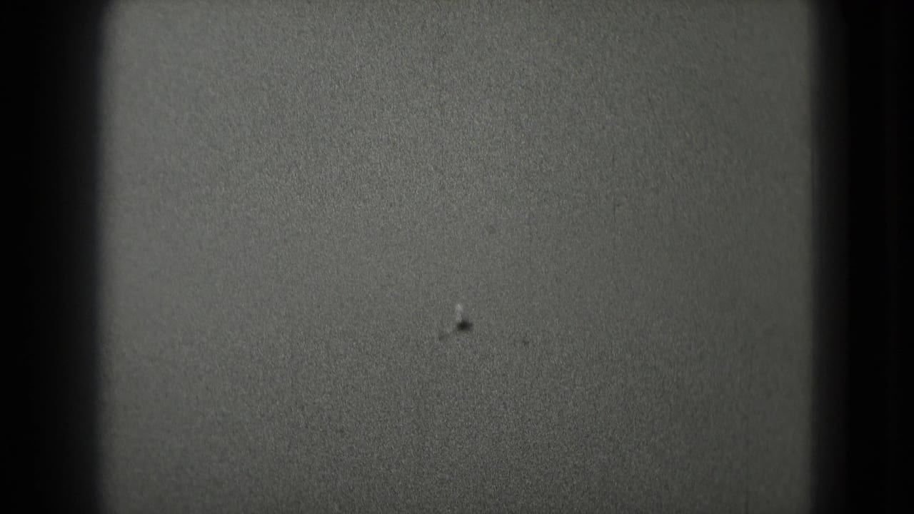 Grainy 8mm frame from the Washington DC clip showing mostly open sky or exposure field with dark rounded film borders.