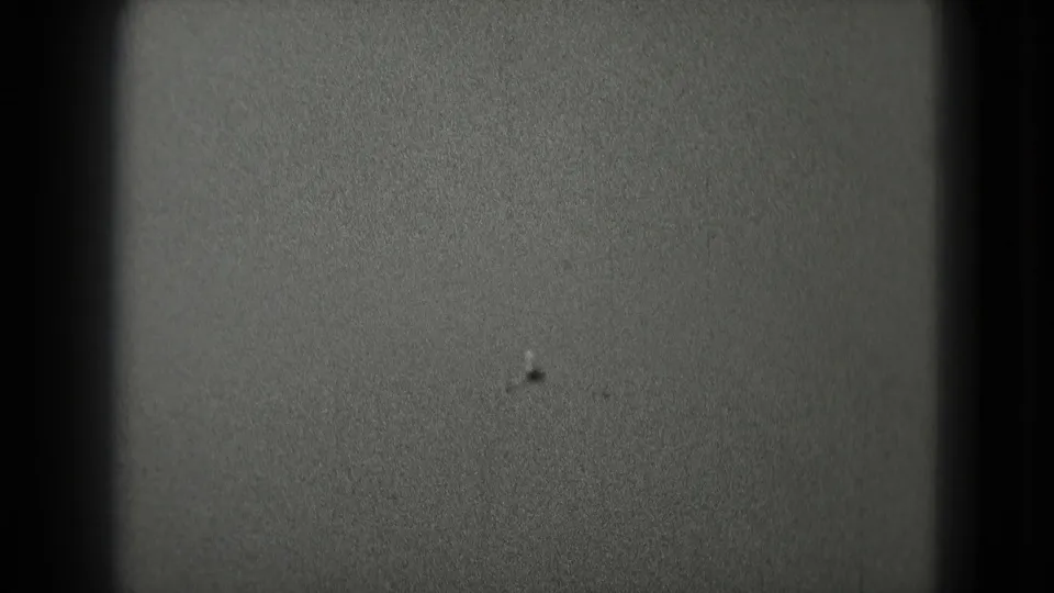 Grainy 8mm frame from the Washington DC clip showing mostly open sky or exposure field with dark rounded film borders.