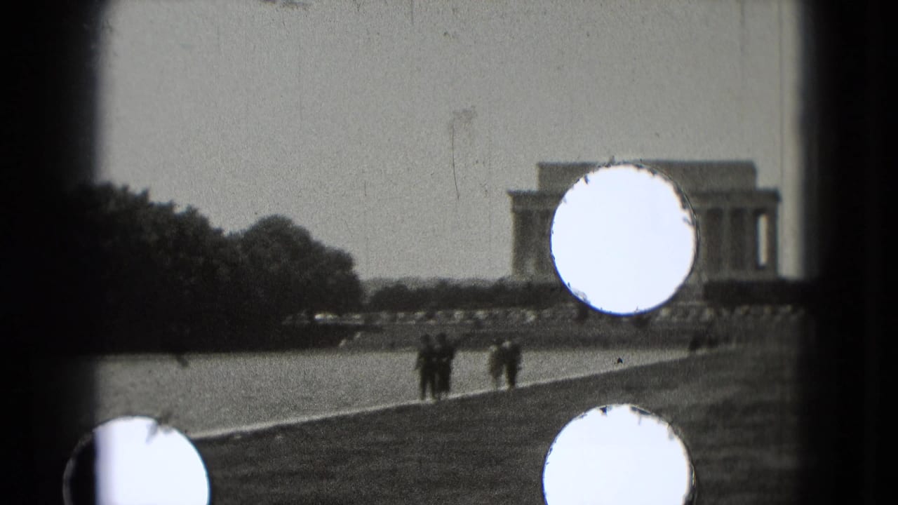 Distant Lincoln Memorial seen across the Reflecting Pool with tourists walking nearby and circular light leaks on the frame.