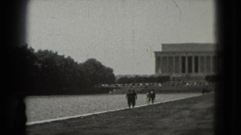 Distant 1975 Washington, DC view of the Lincoln Memorial and Reflecting Pool area, with two tourists walking through the National Mall landscape.