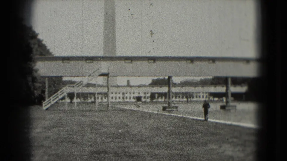1975 Washington, DC home-movie frame looking toward the Washington Monument area, with a walkway, Reflecting Pool edge, and a distant pedestrian.