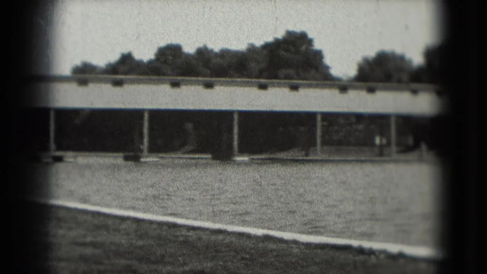 Black-and-white 1975 Washington, DC home-movie view of a broad paved area under a long low span, with trees and columns behind it.