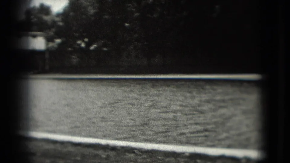 1975 Washington DC home-movie frame showing water, trees, shoreline, and a distant structure in heavy vignette.