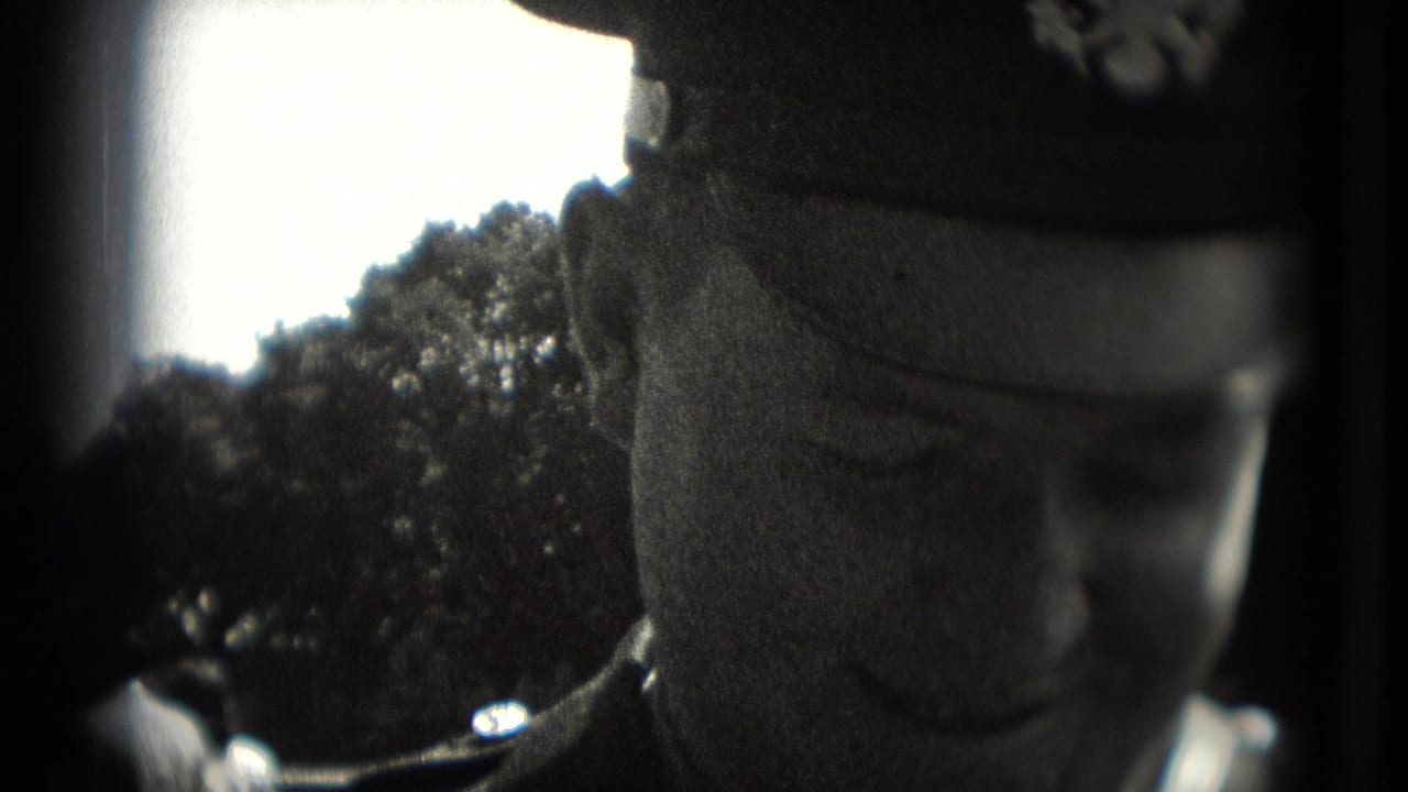 Close 1975 Washington DC frame of a uniformed man in a cap, partially cropped against trees and bright sky.