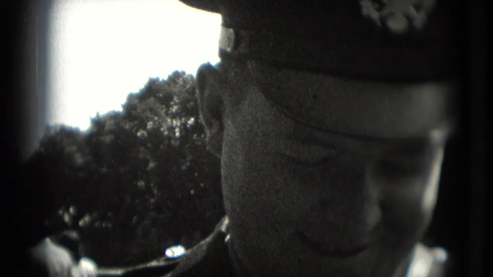 Close 1975 Washington DC frame of a uniformed man in a cap, partially cropped against trees and bright sky.