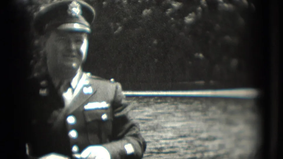 1975 Washington, DC home-movie frame showing a uniformed man in a cap near water and trees.