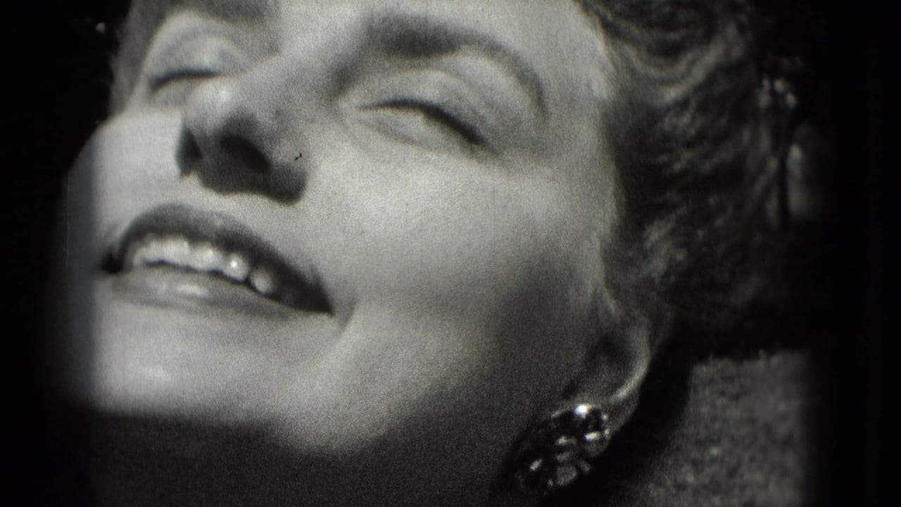 1975 Washington, DC home-movie frame of an adult woman smiling with eyes closed, decorative earring visible, and strong sunlight across her face.