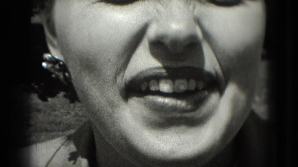 1975 Washington, DC 8mm frame showing an adult woman's cropped face, open mouth, earring, and sunlit features in high-contrast black and white.