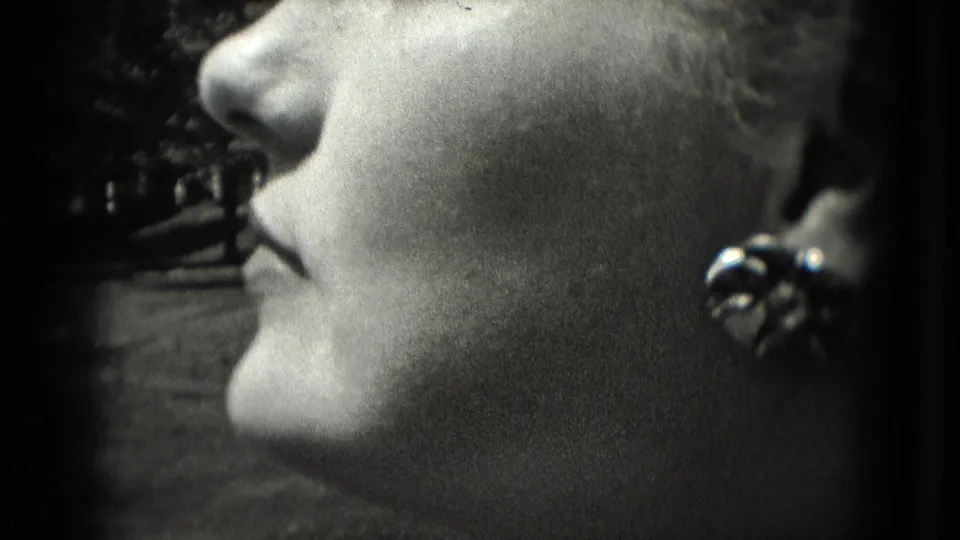 Washington, DC 1975 home-movie frame showing the woman in side profile with lips closed and earring visible.