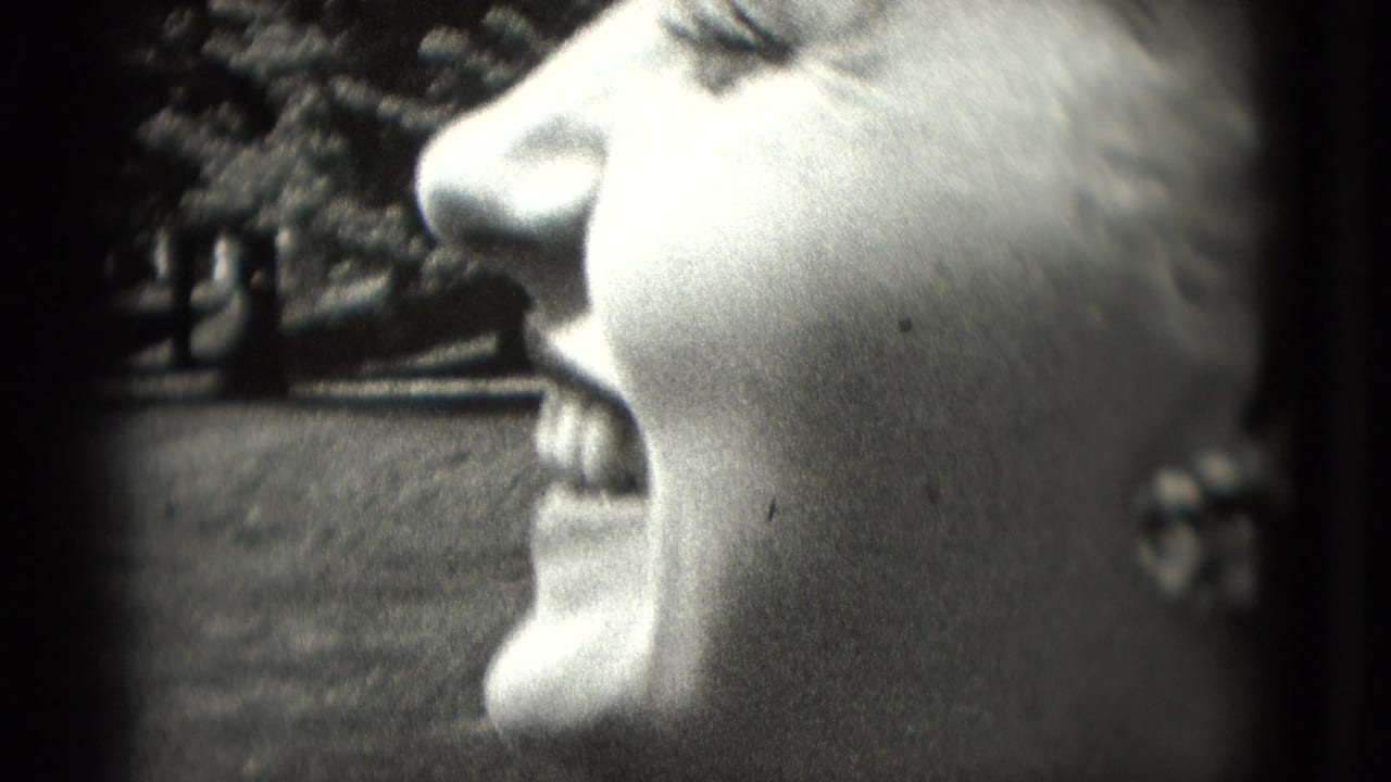 Close-up profile of a woman smiling outdoors in grainy black-and-white film.