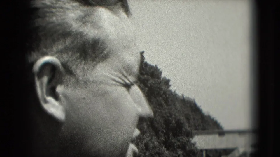 Side view of a man squinting or smiling in sunlight, from a grainy 1975 Washington DC 8mm home-movie shot.