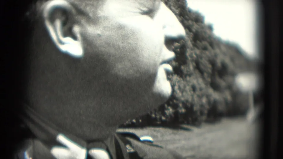 Side-profile close-up of a uniformed man in a cap outdoors, filmed on black-and-white 8mm in Washington, DC in 1975.