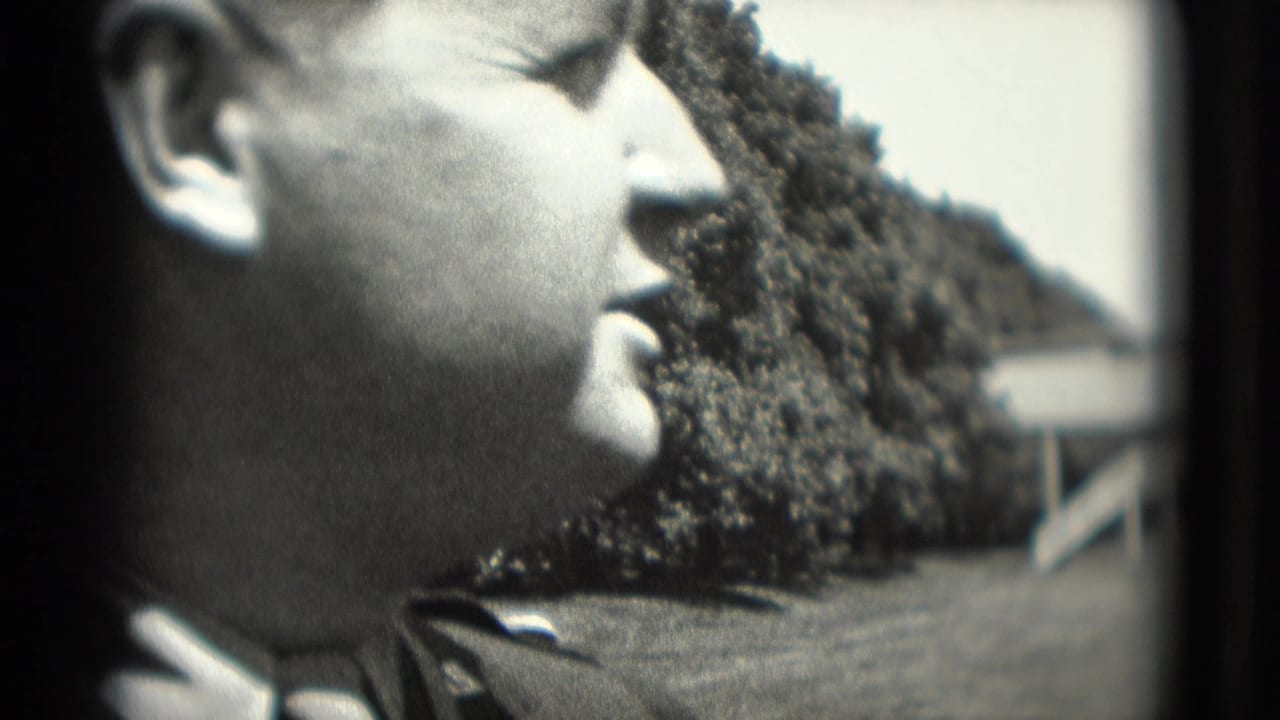 Close 8mm frame of an adult man in profile at a Washington, DC outdoor amusement setting, with trees and ride structures behind him.