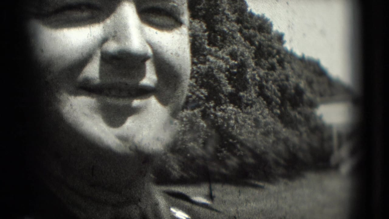 Close adult face with trees and outdoor structures in the background.