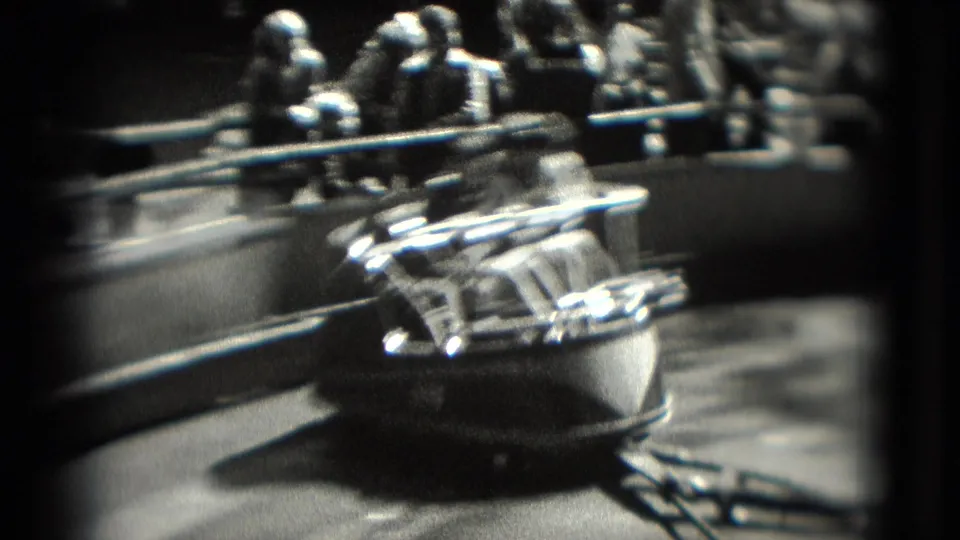 People sit on a small amusement ride in a grainy 8mm Washington, DC home-movie frame, with metal railings and motion blur visible.