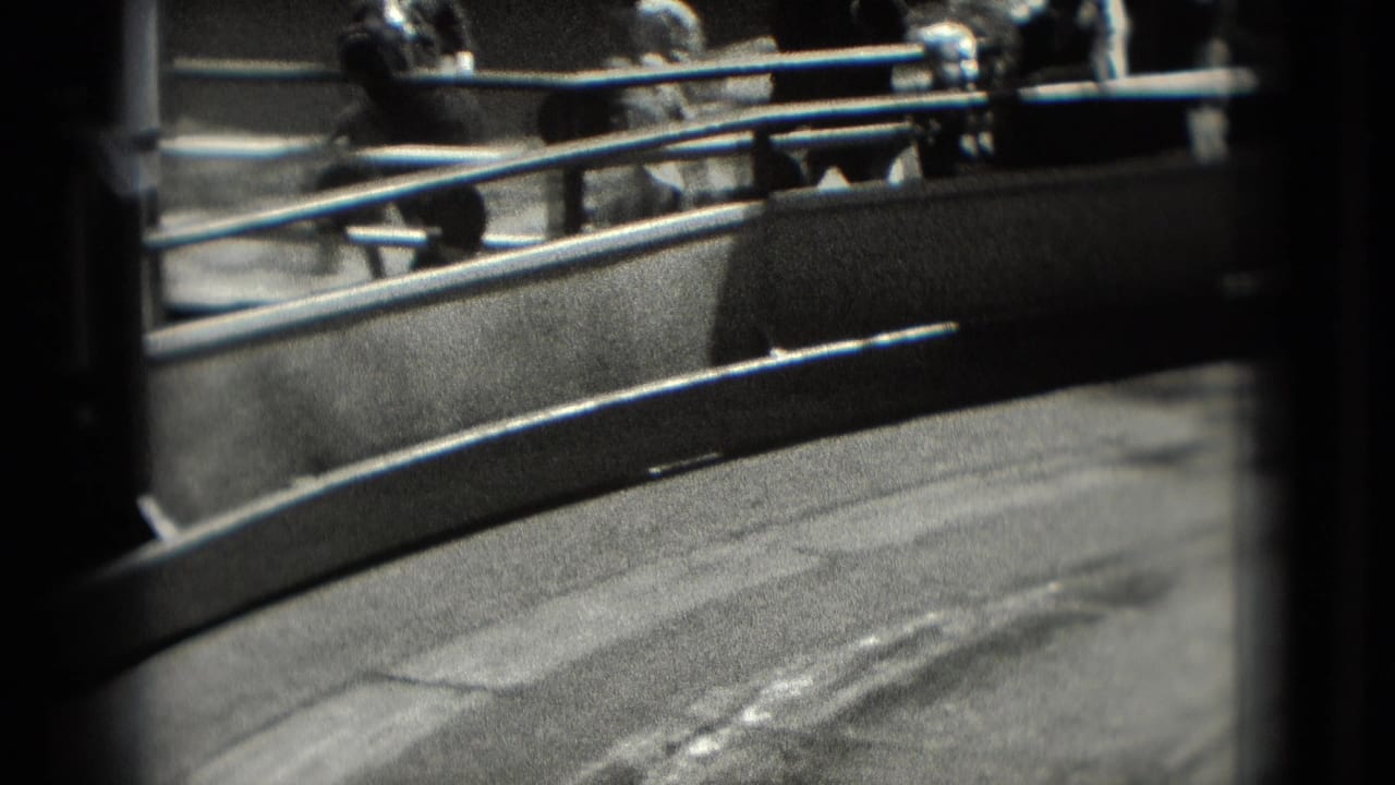 1975 Washington, DC home-movie frame of an amusement ride area with metal rails, seated riders, and a curved platform.