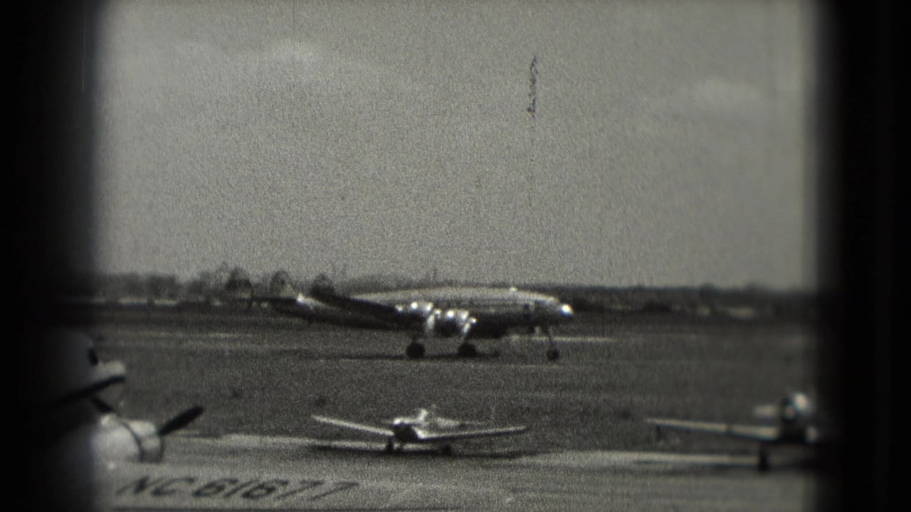 1975 Washington DC airport view with a propeller airliner taxiing past smaller planes on an open tarmac.