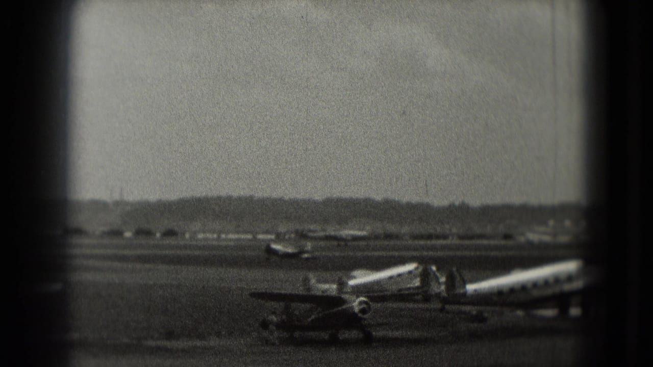 Propeller aircraft parked on a tarmac with a mobile stairway and distant runway beyond.