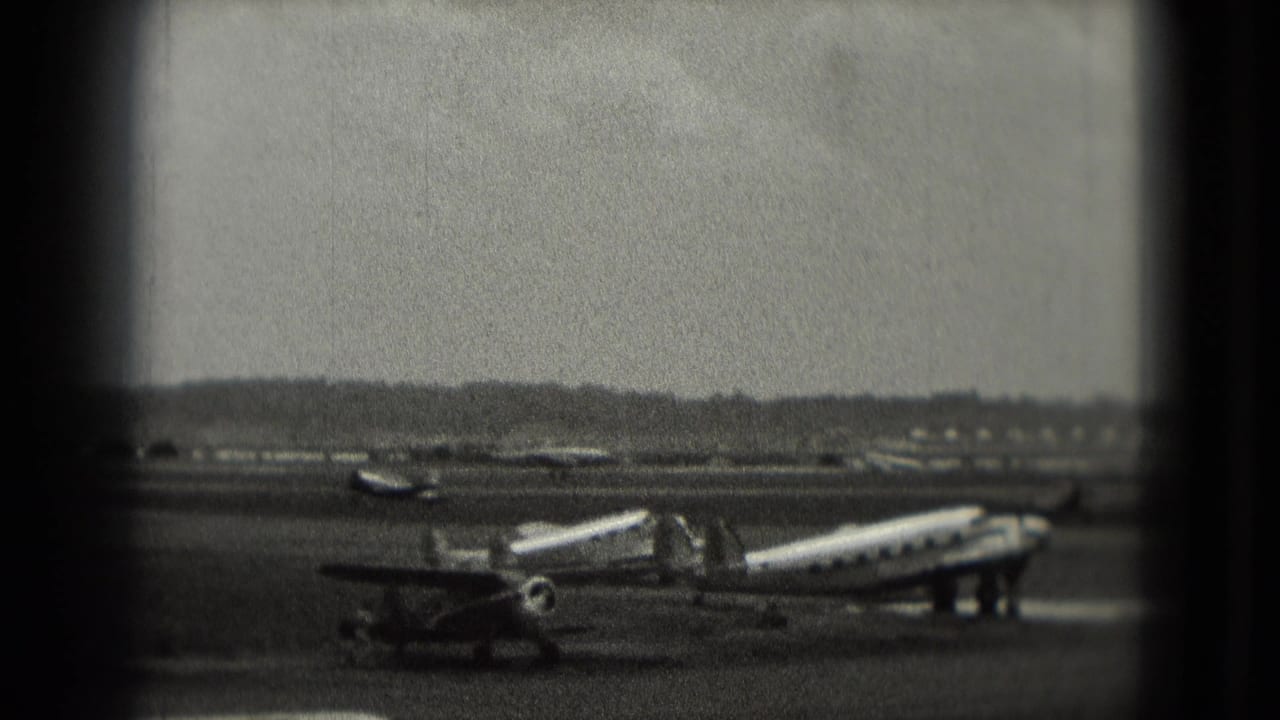 1975 Washington-area airport view with a propeller aircraft, service stairs, distant planes, and dark window-like borders.