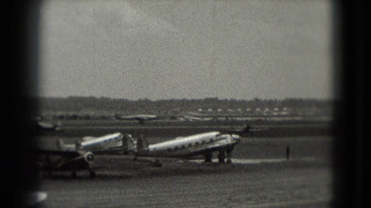 Twin-engine propeller aircraft parked on a tarmac with small figures nearby.