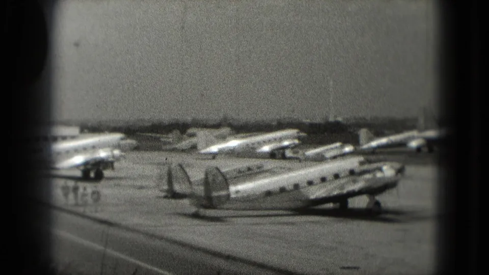 Multiple older propeller aircraft are visible on a paved airfield in the 1975 Washington, DC area home-movie footage.