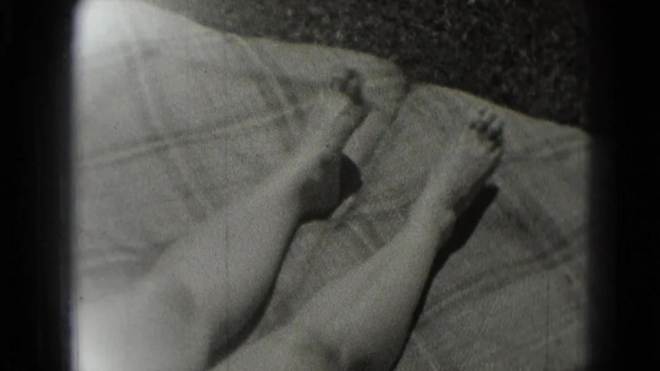 Bare feet and lower legs rest on a blanket in this 1975 Washington DC home-movie frame, with soft focus and visible film grain.