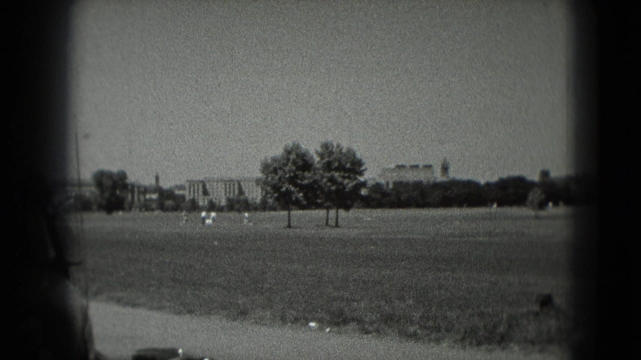 1975 Washington, DC home-movie frame showing an open grassy area, trees, distant buildings, and soft film edges.